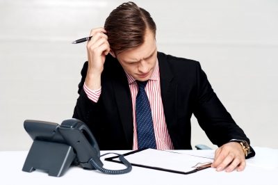 Businessman at desk, confused, scratching head